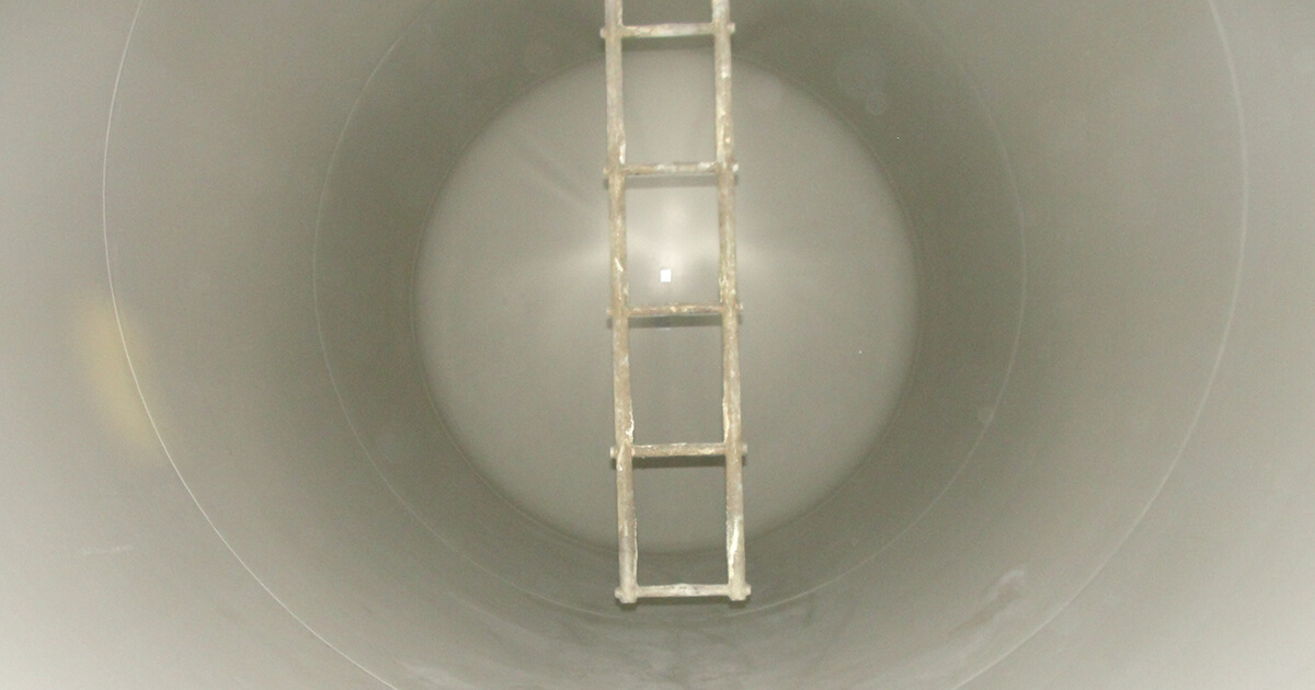 The inside of an empty rail tank car, including its interior lining and access ladder.