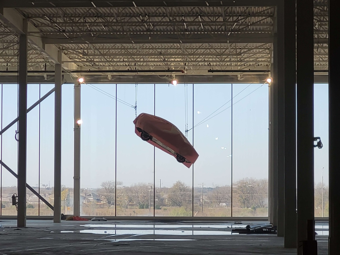 A car is suspended from cables inside the under-construction EV manufacturing facility in Austin.