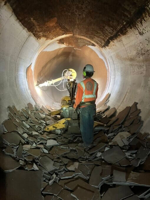 Workers use a jackhammer to break the mortar lining off of the inside surface of the Etiwanda Pipeline in Southern California.