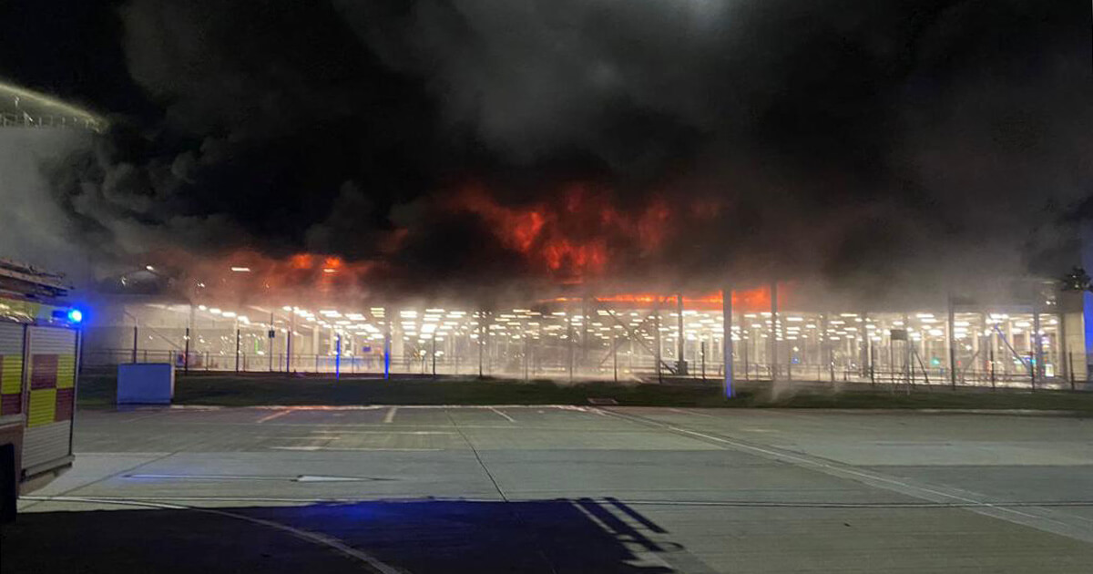 Ground-level view of a fire burning inside a parking garage at London Luton Airport in 2023.