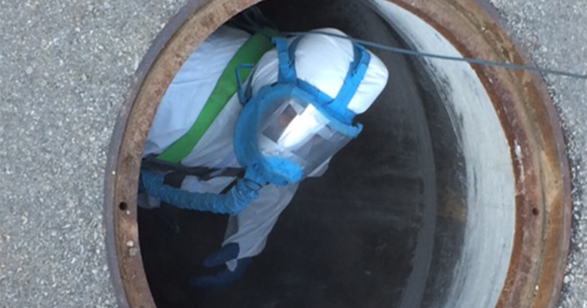 An applicator in a manhole preparing to coat the structure.